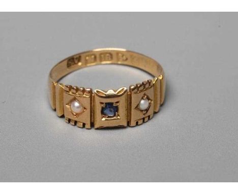AN EDWARDIAN RING, the central small sapphire in rub-over setting and flanked by two seed pearls in shaped panels and stepped