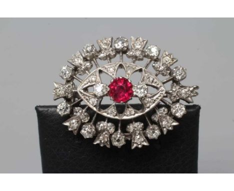 A RUBY AND DIAMOND BROOCH, the central circular facet cut ruby claw set to open borders of old mix cut diamonds to an unmarke