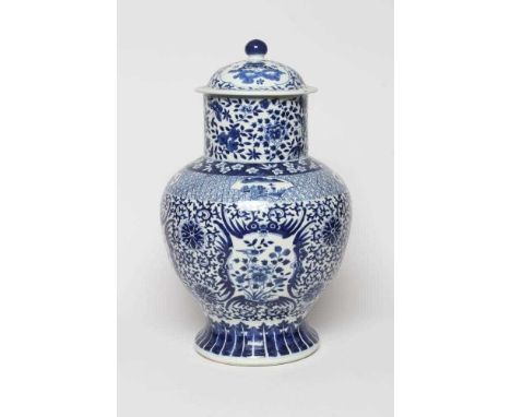A CHINESE BLUE AND WHITE PORCELAIN LARGE JAR AND COVER of baluster form, painted with panels of flowers on a scrolling foliat