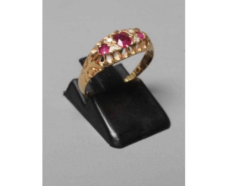 AN EDWARDIAN RUBY AND DIAMOND RING, the three graduated rubies with four diamond points between to carved shoulders and a pla