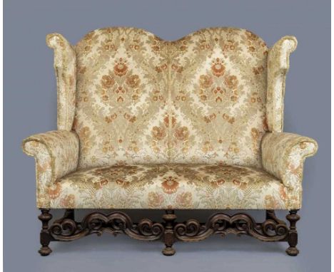A WILLIAM & MARY STYLE WALNUT FRAMED WING SOFA, early 20th century, upholstered in rust and cream floral cut chenille, the do