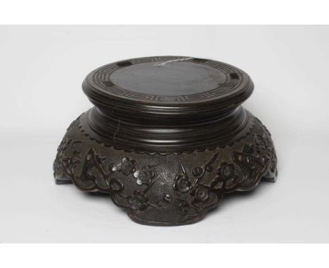 A CARVED CHINESE STAINED WOOD STAND, the incise key carved platform on a domed base similarly carved with flowering prunus on