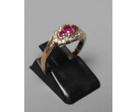 A RUBY AND DIAMOND CROSSOVER RING, the three graduated rubies claw set to a border of small brilliant cut diamonds to a plain