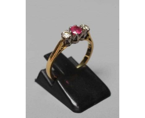 A THREE STONE RUBY AND DIAMOND RING, the central facet cut ruby claw set and flanked by two small brilliant cut diamonds to a