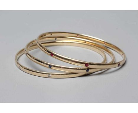A MATCHED SET OF THREE STONE SET 9CT GOLD BANGLES, set with either eight diamonds, rubies or sapphires, London 2005, 2013 &20