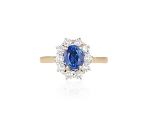 A SAPPHIRE AND DIAMOND CLUSTER RINGThe oval-shaped sapphire within a surround of round brilliant-cut diamonds, mounted in gol