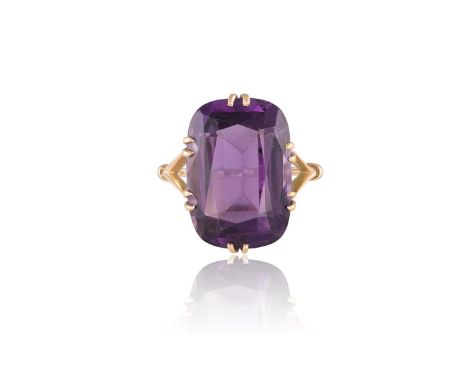 AN AMETHYST COCKTAIL RINGThe rectangular cushion-shaped amethyst within a double six-claw setting, to a bifurcated gold hoop,