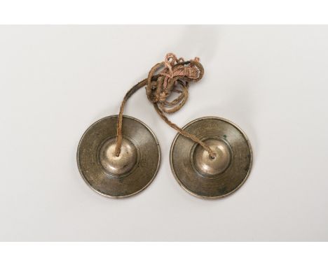 A PAIR OF TWO SMALL TIBETIAN RITUAL CYMBALSTibet, 19th century. The two sacred cymybals (rol-mo) of thick, cast brass and emb