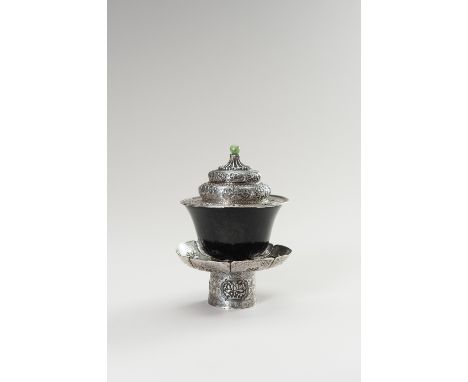 A SILVER AND SPINACH-GREEN JADE BUTTER TEA SETTibet, 19th century. The silver stand with the lobed saucer atop, embossed with