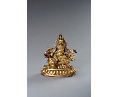 A TIBETAN GILT BRONZE FIGURE OF KUBERA WITH BUDDHIST LIONTibet, first half of the 20th century. The gilt bronze figure with f