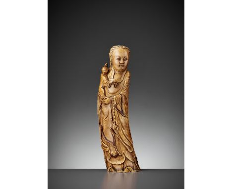 AN IVORY FIGURE OF GUANYIN AND CHILD, LATE MING DYNASTYChina, 16th to early 17th century. The Goddess of Mercy boldly carved 