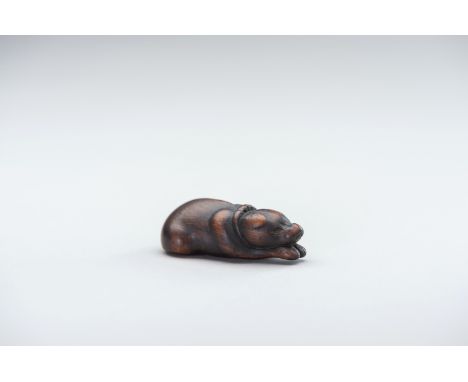 A CHARMING OLD WOOD NETSUKE OF A RECLINING DOGJapan, 18th centuryA stylized netsuke with a very appealing aji (patina). The d