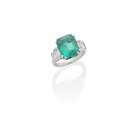 AN EMERALD AND DIAMOND RINGThe step-cut emerald, weighing 6.88 carats, between shoulders of baguette-cut diamonds, ring size 