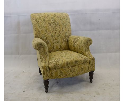 An Edwardian upholstered armchair, with turned front supports and ceramic castors with floral and mustard upholstery 