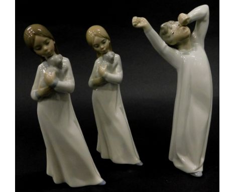 A Lladro porcelain figure of a young boy wearing a night dress yawning, and two similar Nao figures each with a puppy. (3)