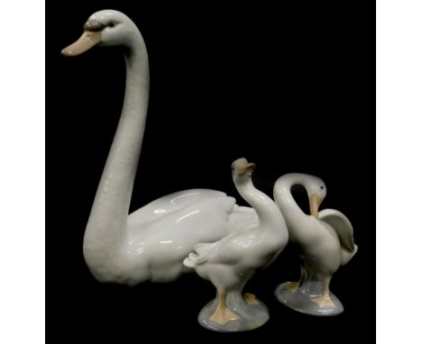 A Lladro porcelain figure of a swan, 21cm high, and two small geese. (3)