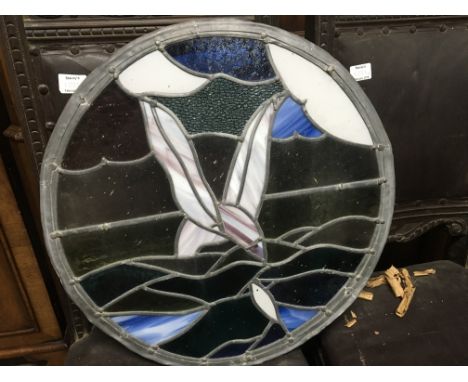 A circular lead light panel in the form of a stylistic bird and fish.