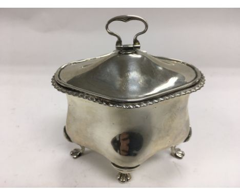 A silver tea caddy with parcel gilt interior and raised on four lion paw feet.