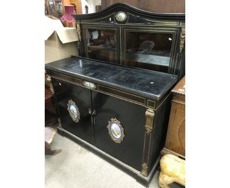 A black and gilt cabinet with painted ceramic lozenge decoration, fitted with two glazed doors over two cupboard doors below.