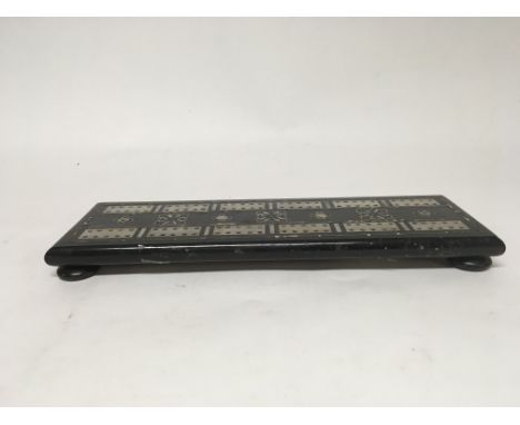 An ebony and mother of pearl cribbage board with one end piece missing. Includes a packet of cribbage pieces.
