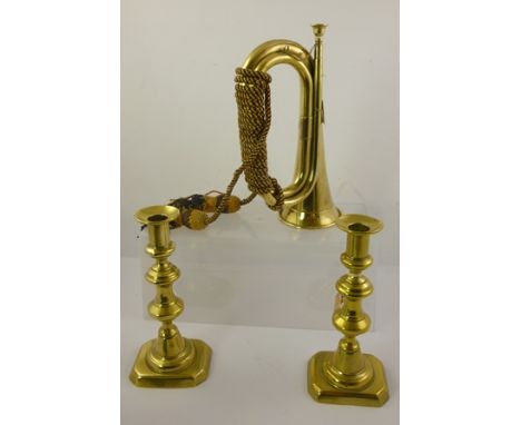 A BRASS MILITARY BUGLE with tassels, together with a PAIR OF 19TH CENTURY BRASS CANDLESTICKS, 22cm high 