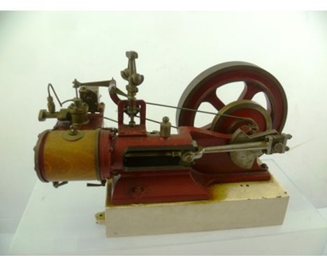 A HORIZONTAL SINGLE PISTON ENGINE with cast fly wheel, red painted, 18 x 28cm 