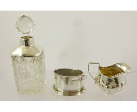 A SILVER CREAM JUG with fluted belly decoration, an oval silver MATCH HOLDER, and a white metal mounted lead crystal SPIRIT D