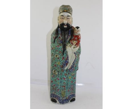 A 20TH CENTURY CHINESE CERAMIC FIGURE of a standing wise man cradling a child, painted in polychrome famille rose decoration 