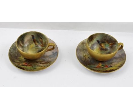 JAMES STINTON A PAIR OF ROYAL WORCESTER COFFEE CUPS AND SAUCERS, the cup interiors hand painted with pheasants in woodland, e