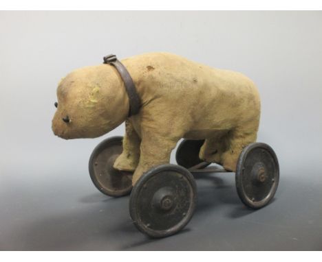 A stuffed toy bear on wheels, possibly Steiff, (worn)