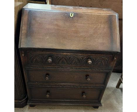 A 20th century oak bureau, with a sloping fall and three long drawers on bracket feet