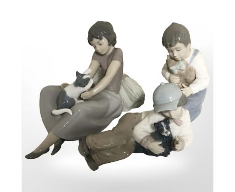 Two Nao figures of boys and a further figure of a girl playing with a kitten.