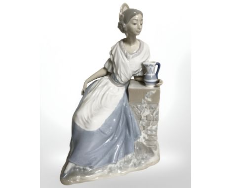 A Nao figure of a lady seated by a stone pillar, height 31 cm.