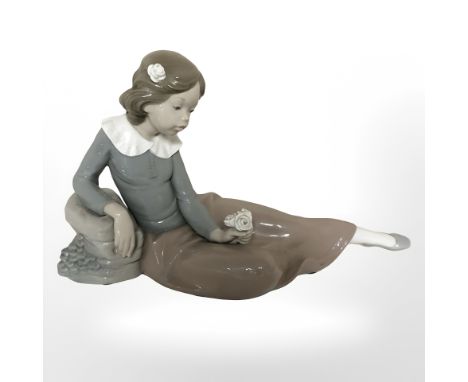 A Nao figure of a seated girl holding a rose.