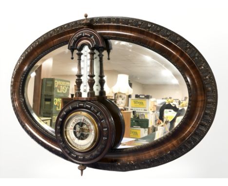A mahogany oval bevelled mirror, width 82 cm, and a barometer. 
