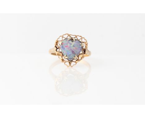 An opal triplet ring, set with a heart shaped opal triplet, surrounded by a border of open heart design metalwork, stamped 9c