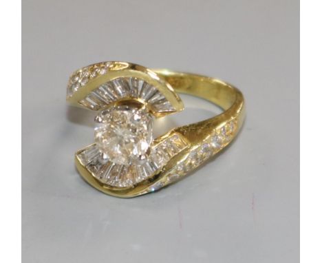 A modern 18k gold and single stone diamond ring and baguette cut diamond setting, the central stone weighing in excess of 0.9