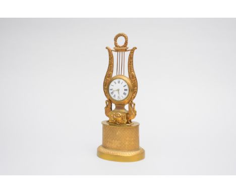A gilt metal lyre mantel timepiece, the movement marked F.B.Adams, St.John's Sq., London, the case with flower garland finial