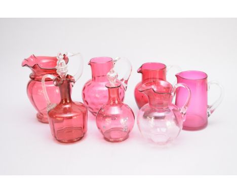 Fifteen assorted cranberry glass jugs and decanters, predominantly Victorian, including dimple and lobed glass examples and a