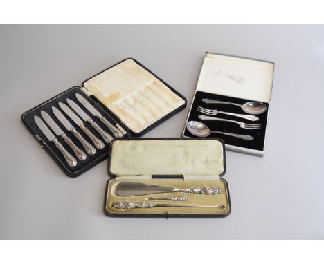 A cased set of six silver handled knives, together with a cased silver mounted button hook and shoe horn set and a cased plat
