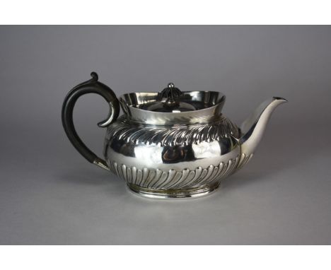 An Edwardian Goldsmiths &amp; Silversmiths Co Ltd silver teapot, London 1908, of oval half wrythen form with ebonised handle 