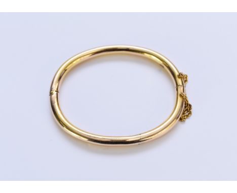 A yellow metal hollow bangle, engraved 'Evelyn', with attached safety chain, weight approx 13.1g