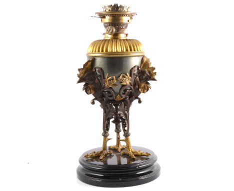 Bronzed and gilt metal oil lamp, cast base with cockerel masks and feet, circular base, height 45cm.