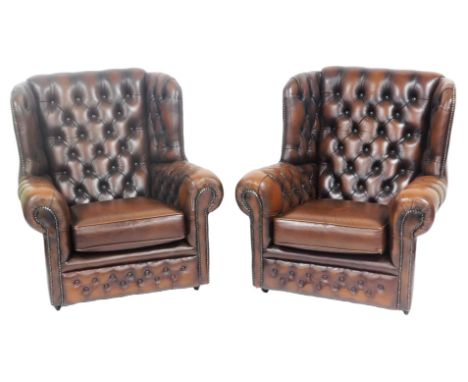 A pair of brown leather wing back armchairs, with button back and arms, and loose cushion seats, 78cm wide.