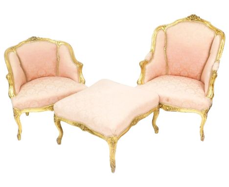 A pair of late Victorian French style parcel gilt arm chairs, with foliate carved crest rail, upholstered in overstuffed pink