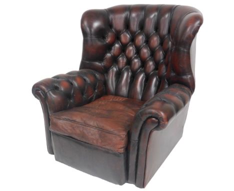 A brown leather wing armchair, with button back and arms, and loose cushion seat, 94cm wide.
