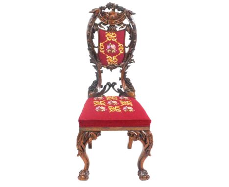 A late 19thC continental walnut hall chair, with a floral and foliate carved crest rail, shield back, overstuffed tapestrybac