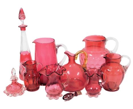A group of Victorian and later cranberry glass jugs, a scent bottle, decanter and stopper, and a further stopper. (a quantity