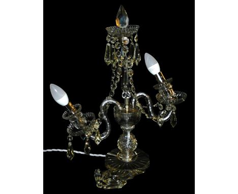 A cut glass table lamp, of twin branch candelabrum form, with tear and brilliant cut drops and swags, raised on a faceted cir