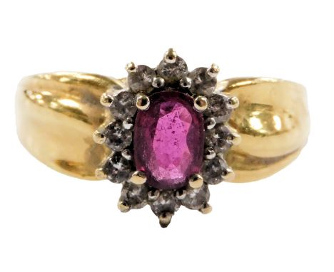 An 18ct gold ruby and diamond ring, the oval cut ruby in a surround of twelve brilliant cut diamonds, size J 1/2, 4.5g.